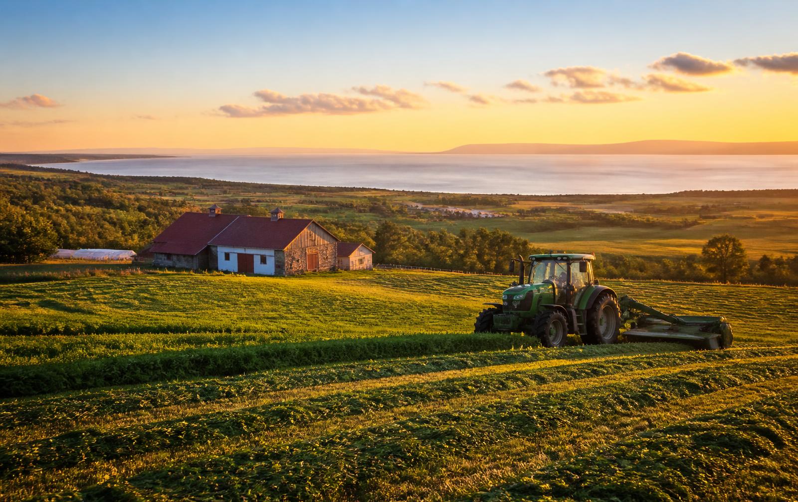 Ferme du Bas-Saint-Laurent au coucher du soleil avec tracteur dans un champ
